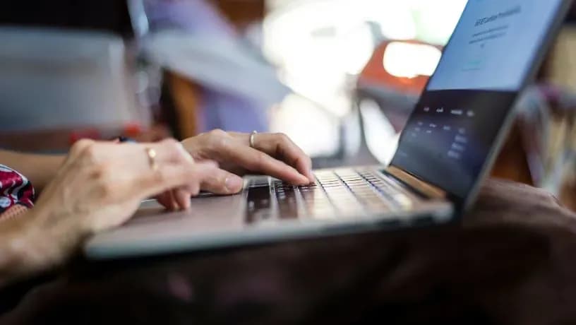 Close-up of hands typing on a laptop keyboard, representing digital financial management.